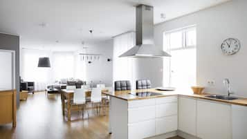 A modern kitchen with a central island, white cabinetry, and a stainless steel range hood.