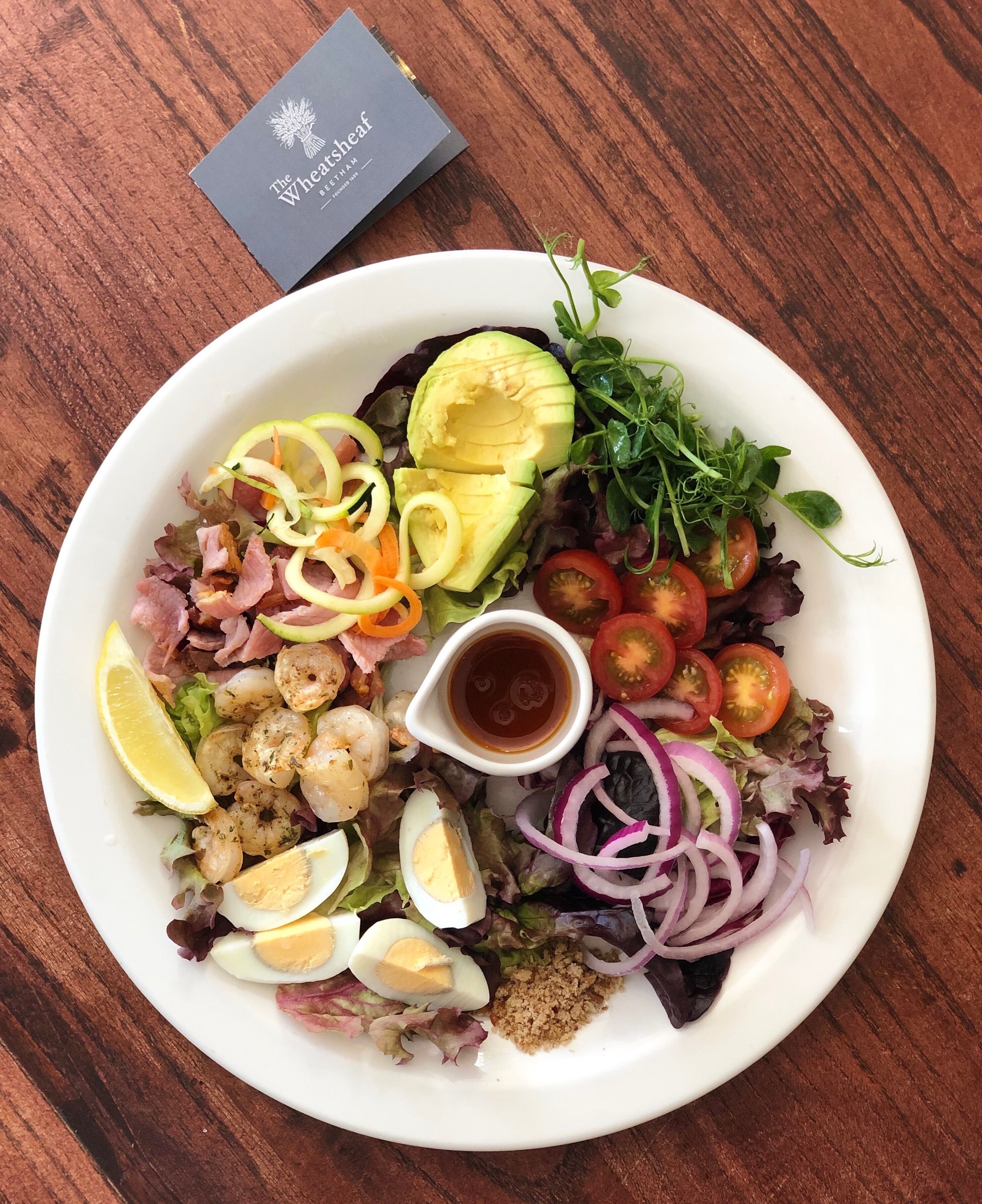 Ein Teller Essen mit verschiedenen Zutaten, darunter Avocado, Garnelen und Eier.