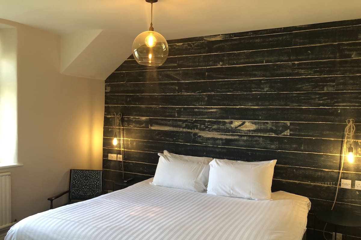 A bedroom with a large bed, a wooden headboard, and two wall-mounted lights.