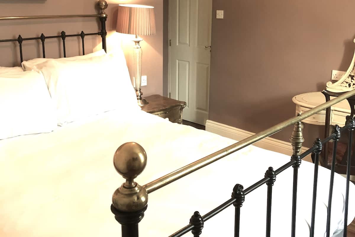 A neatly made bed with a headboard, a bedside lamp, and a framed picture on the wall.