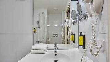 A modern bathroom with a white sink, a handheld hair dryer, and a mirror.