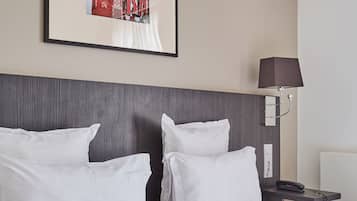 Habitación de hotel con una cama grande, cabecero, mesita de noche con lámpara y un cuadro enmarcado en la pared.
