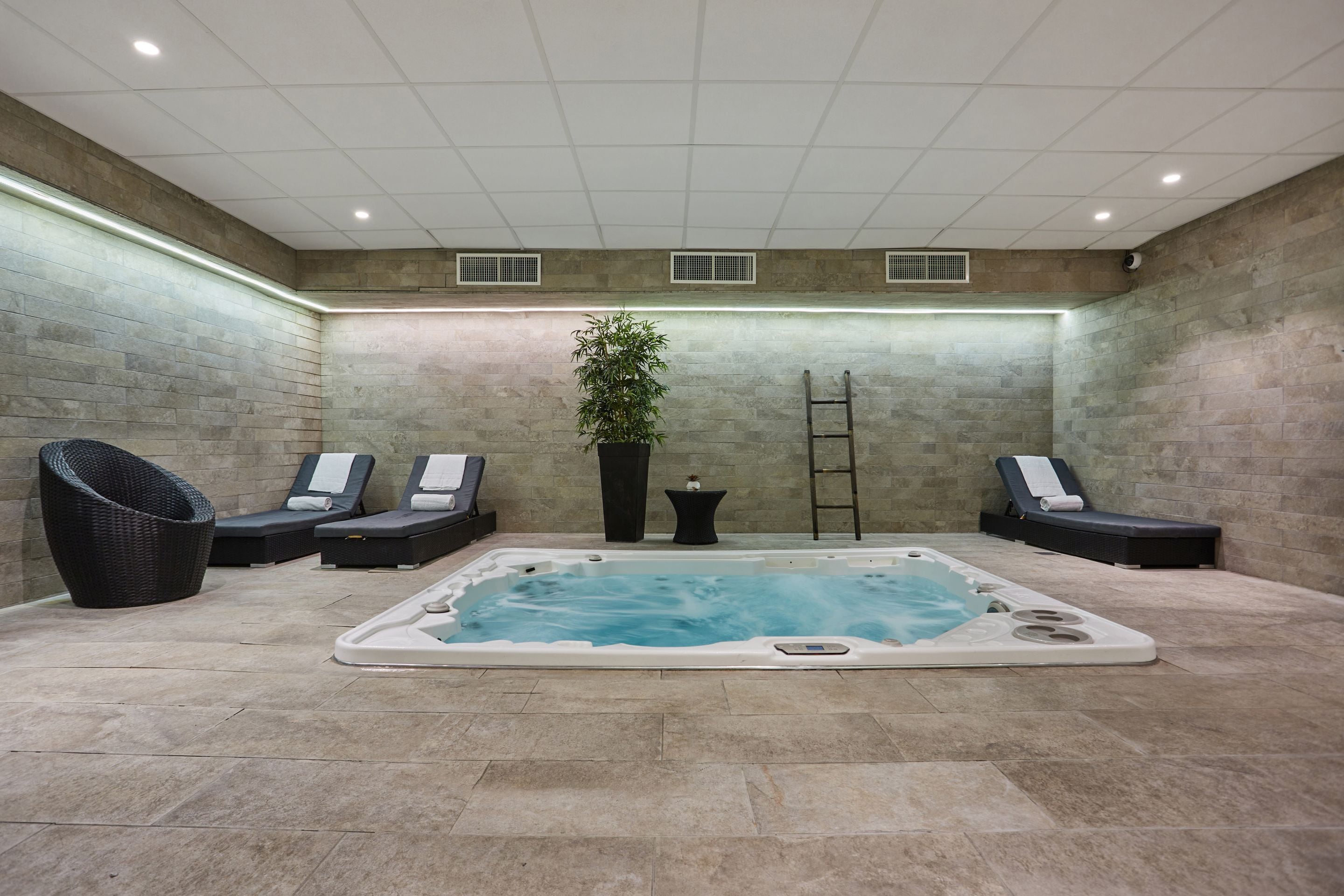 A spa area with a hot tub, lounge chairs, and a potted plant.