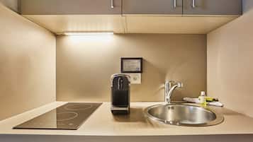 A compact kitchenette with an induction cooktop, a built-in sink, and a compact dishwasher.