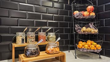 Estación de aperitivos con frascos de frutos secos, frutas deshidratadas y naranjas frente a un muro de ladrillo negro.