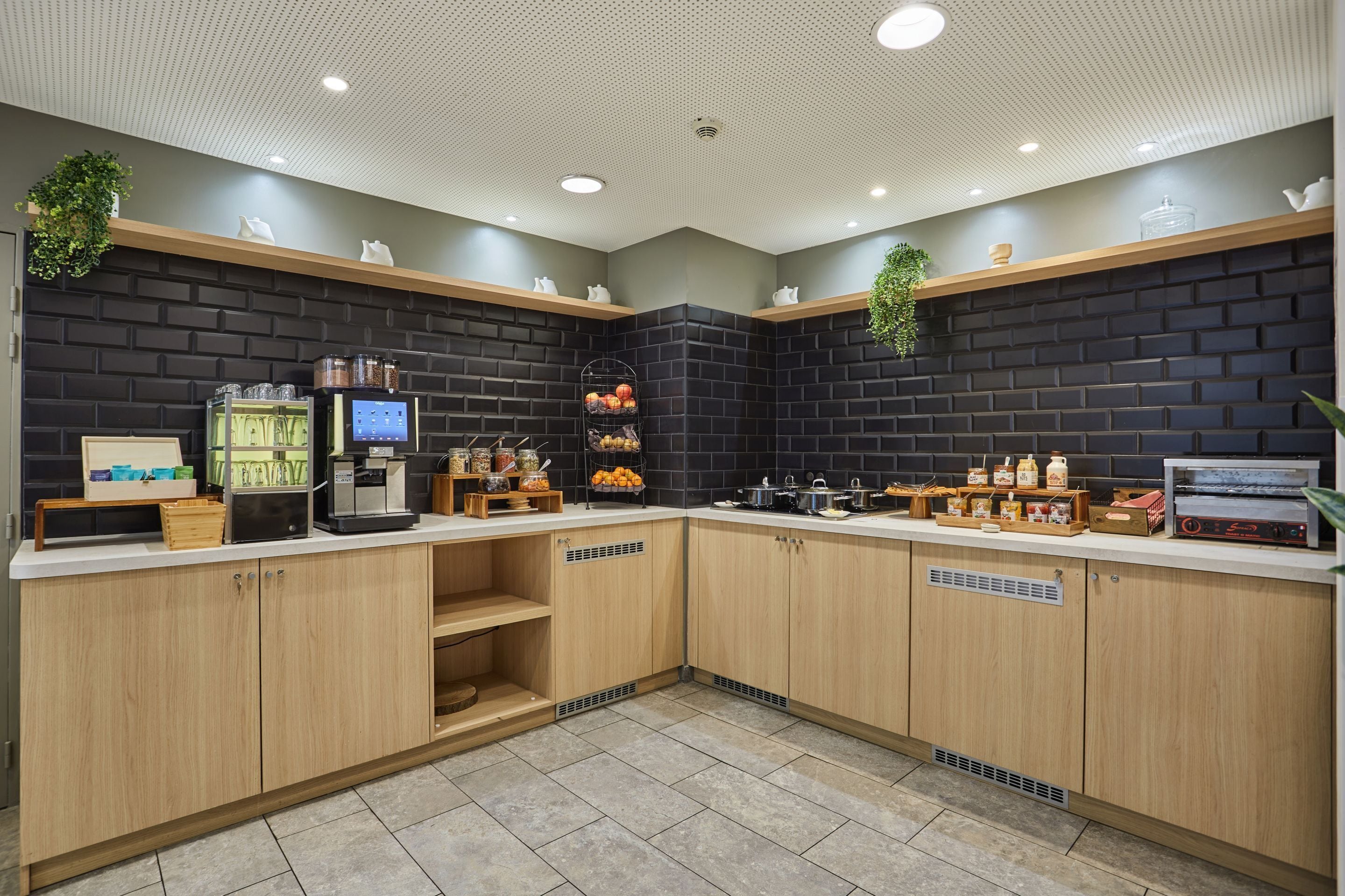 A modern kitchen with wooden cabinets, a coffee machine, and various kitchen appliances.
