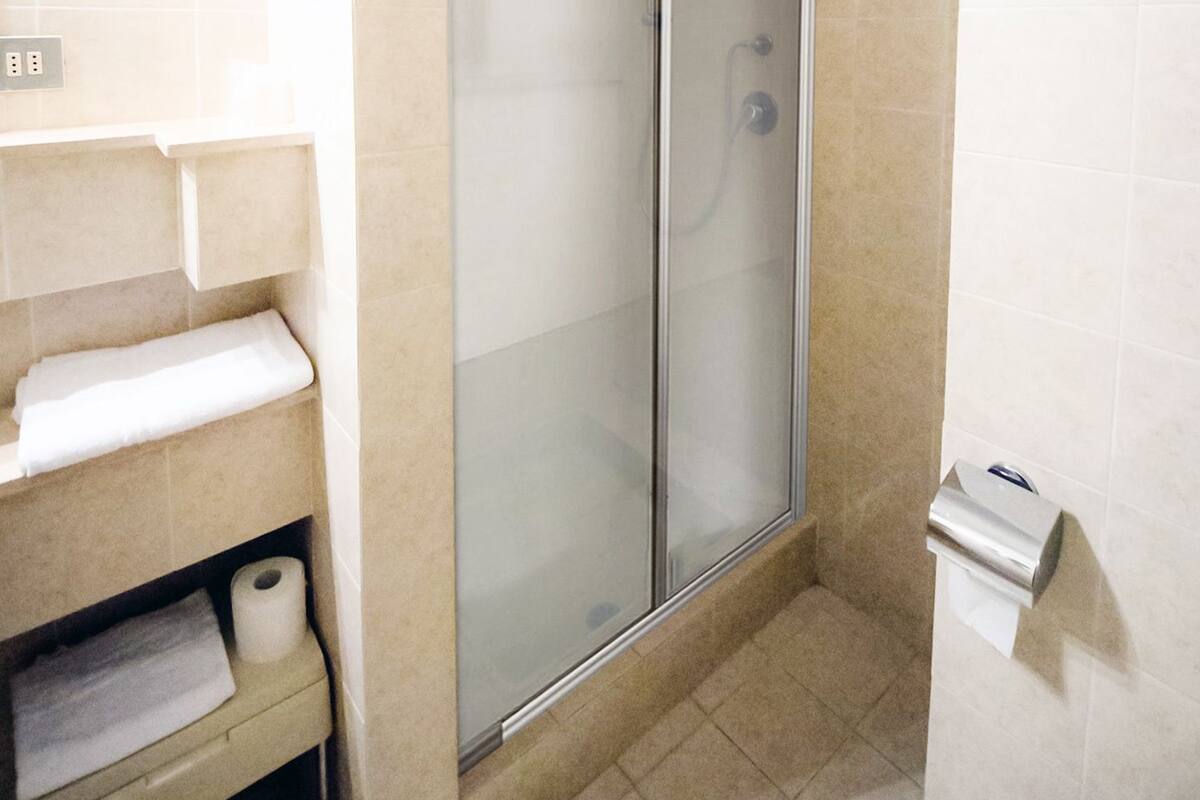 Ein Badezimmer mit einer Duschkabine, einer Toilette und einem Waschbecken mit Handtuchhalter.