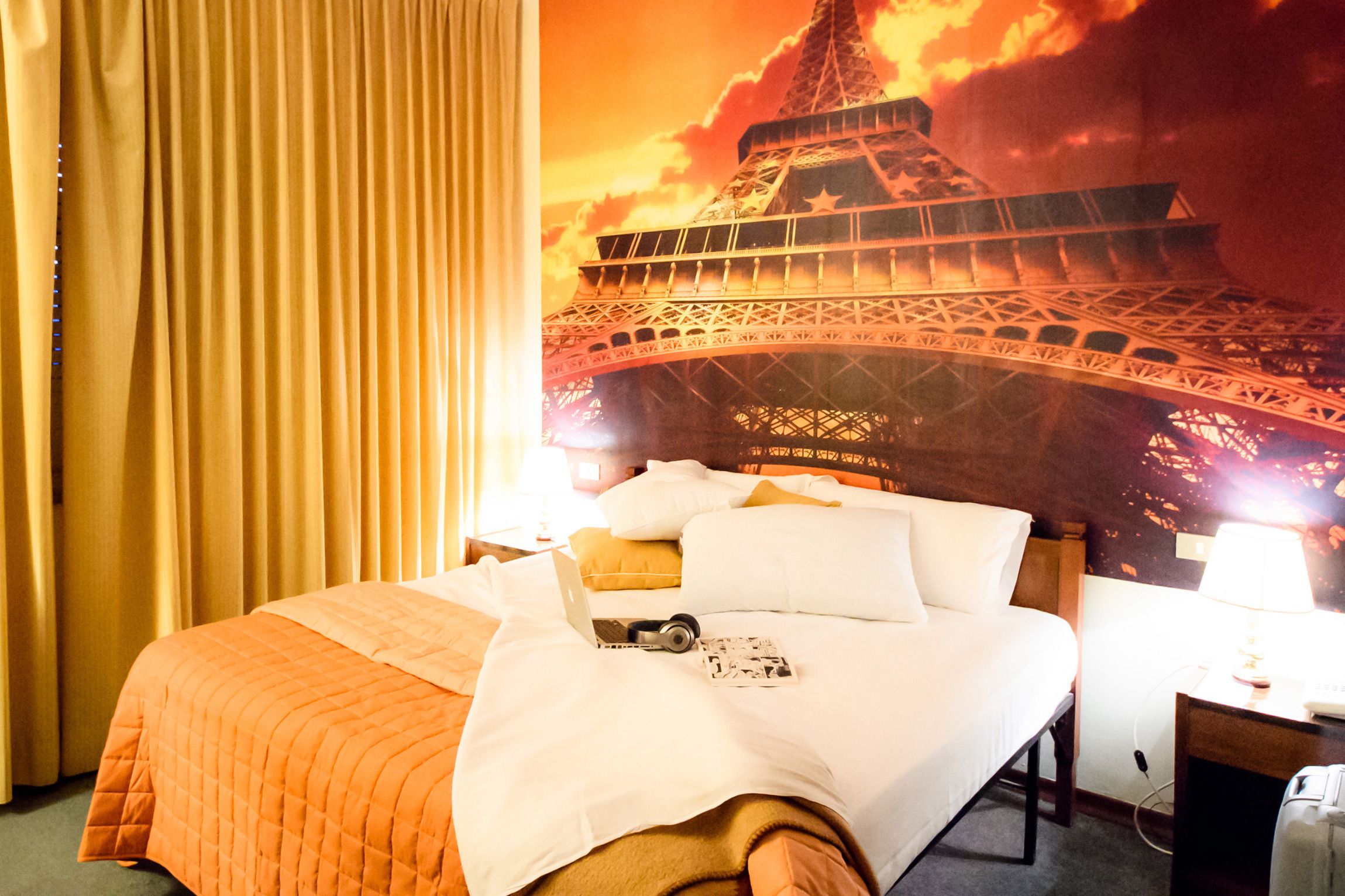 Une chambre d’hôtel avec un lit, un ordinateur portable et un cadre photo posé sur le lit.