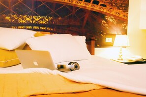 A bed with a laptop, a camera, and a lamp on a nightstand. - Hotel Palombella (Frosinone)