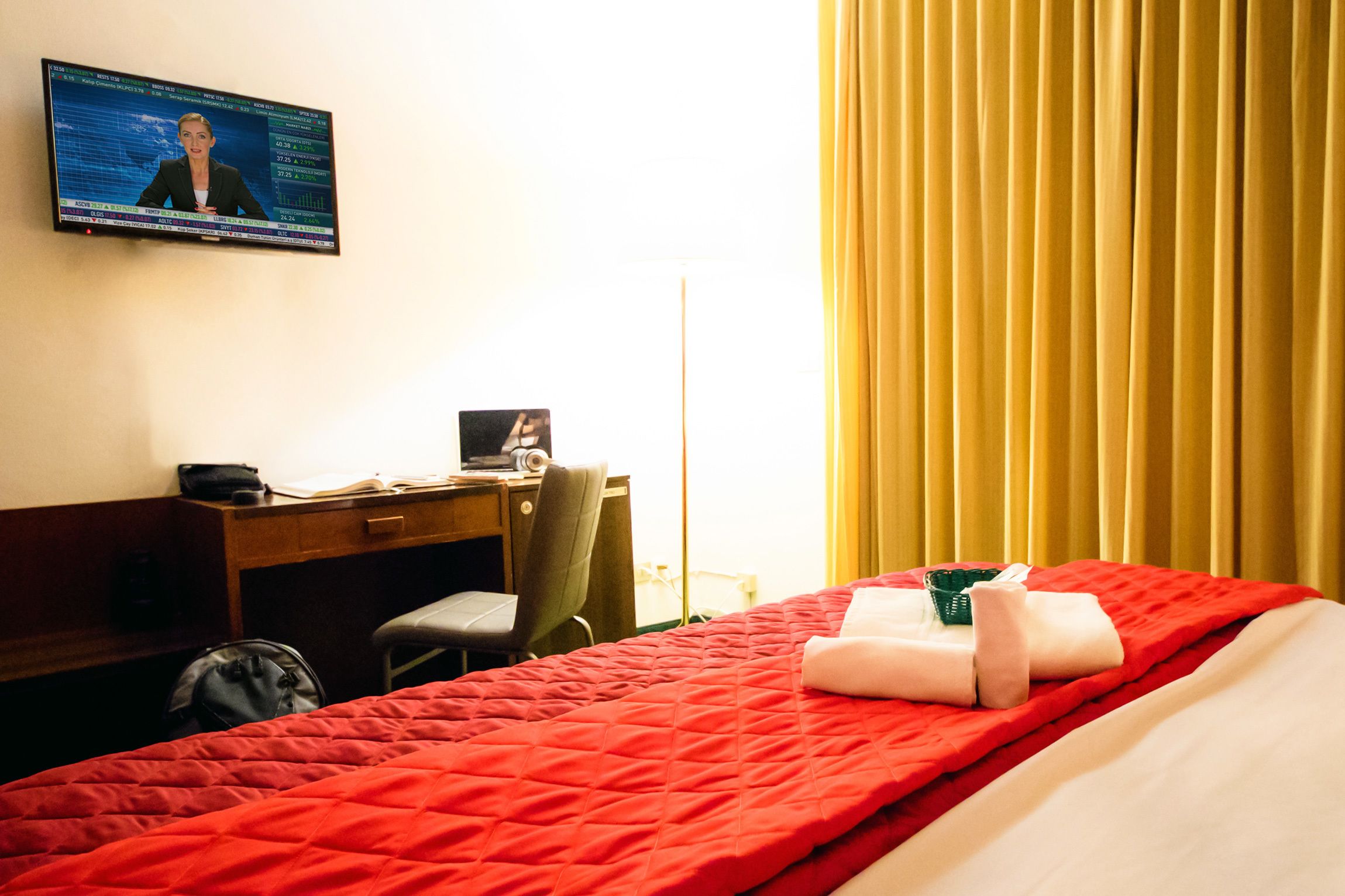 A hotel room with a bed, a desk, a chair, a television, and a window with curtains.