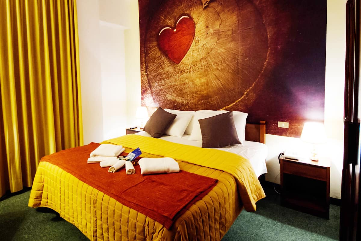 Ein Hotelzimmer mit Bett, Nachttisch, Lampe und einer großen Wandmalerei.