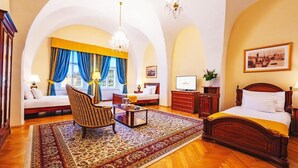 A spacious hotel room with a large bed, a sofa, a chair, a TV, and a desk. - Josephine Old Town Square Hotel - Czech Leading Hotels (Prague)