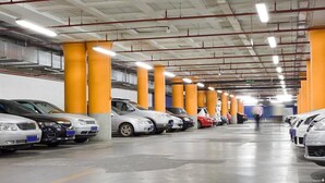 A multi-level parking garage with rows of parked cars, yellow pillars, and overhead lighting. - Josephine Old Town Square Hotel - Czech Leading Hotels (Prague)