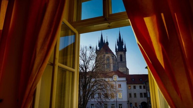 An open window with curtains, revealing a view of a historic building with spires. - Josephine Old Town Square Hotel - Czech Leading Hotels (Prague)