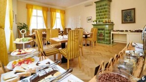 A dining area with striped chairs, a buffet table with various food items, and a green tiled fireplace. - Josephine Old Town Square Hotel - Czech Leading Hotels (Prague)