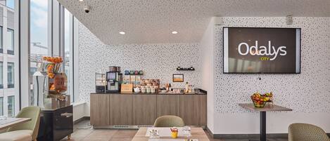 A modern interior with a dining area, a kitchen counter, and a large screen displaying "Odaly's CITY".