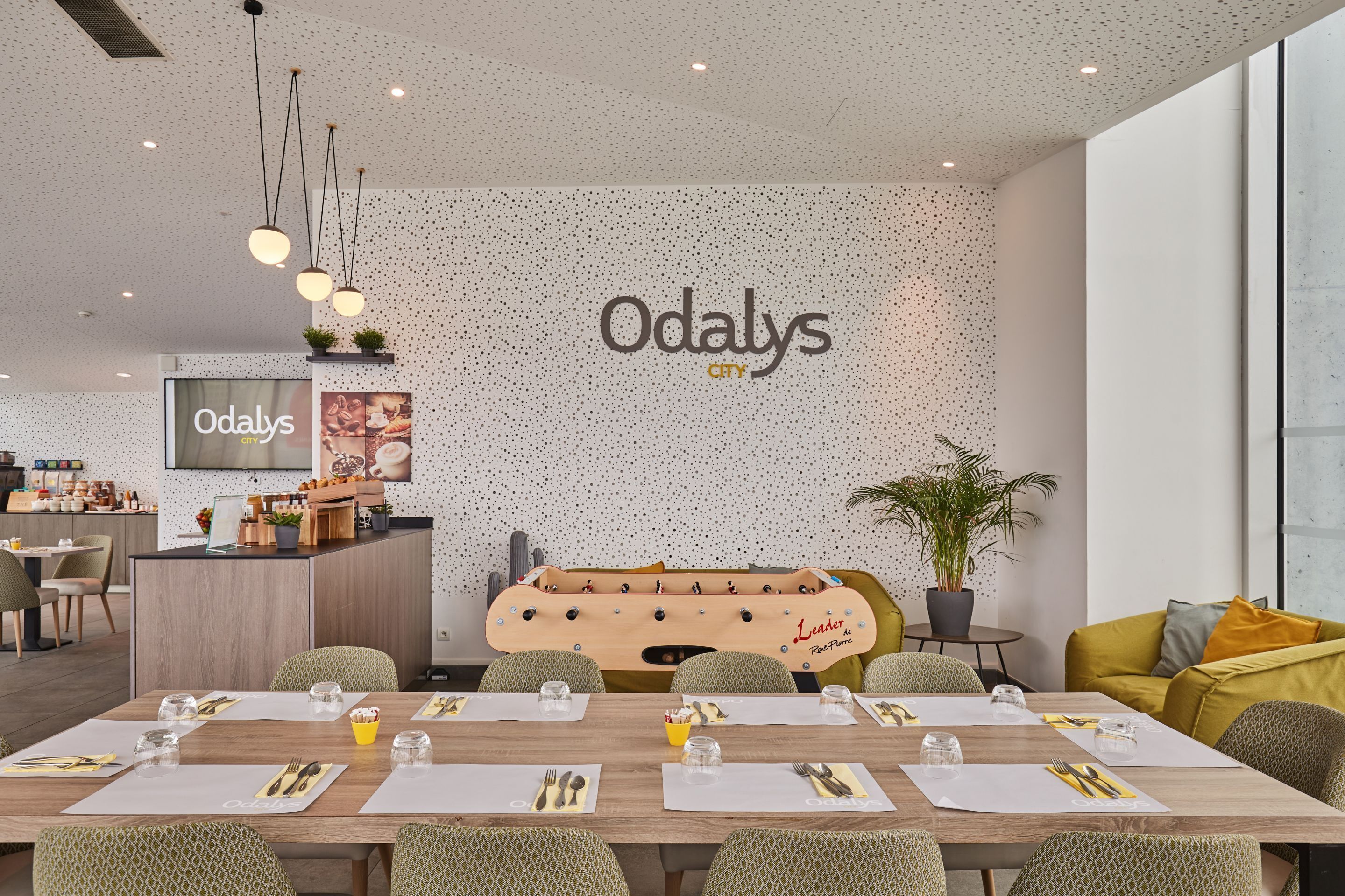 A modern dining area with a long table set for a meal, a bar area, and a seating area with a sofa.