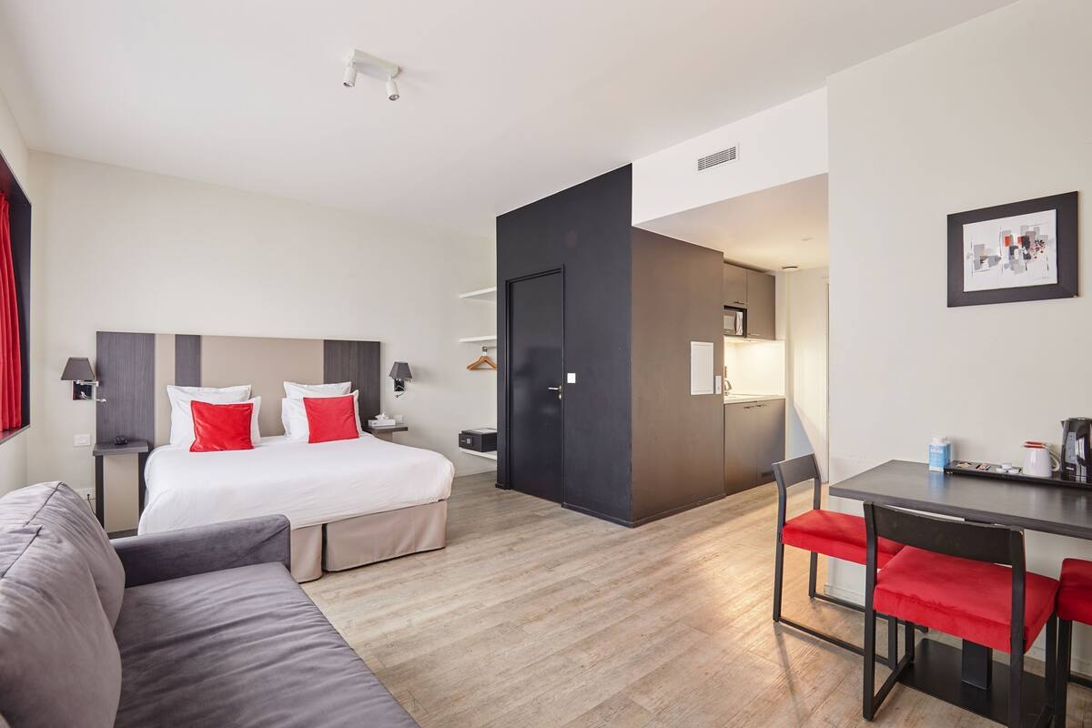 Una habitación de hotel moderna con cama, sofá, escritorio y silla.