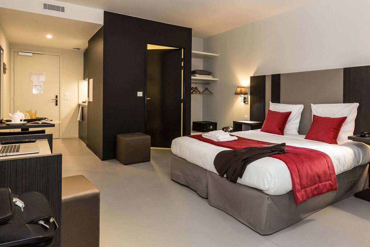 Una habitación de hotel moderna con una cama grande, mesitas de noche, un escritorio con una computadora portátil y una zona de estar.