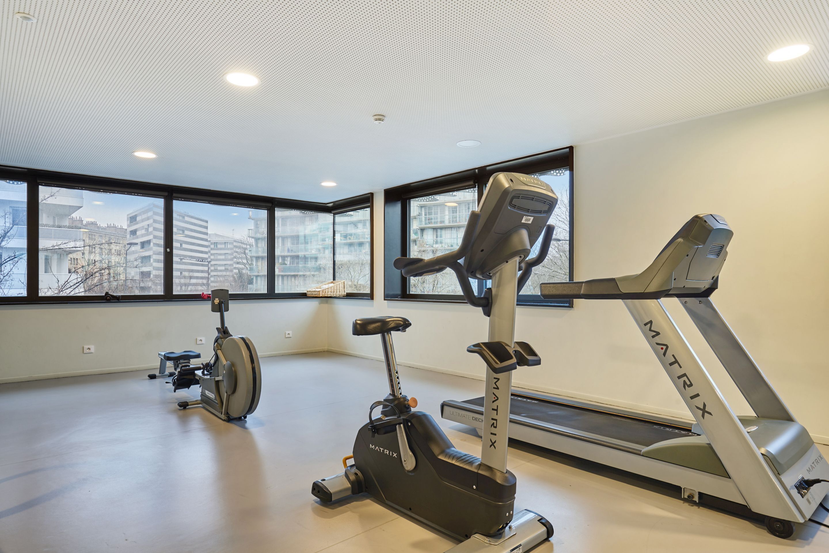 A gym with a treadmill, stationary bike, and elliptical machine.