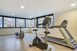 A gym with a treadmill, stationary bike, and elliptical machine. - Appart Hotel Odalys City Paris XVII (Paris)