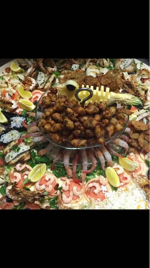 A buffet with a variety of seafood, including shrimp and fish, arranged on a large platter. - Ai colli (Teolo)
