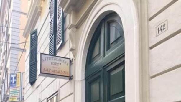 Una calle estrecha con un edificio que tiene una puerta verde y un letrero que indica un restaurante.