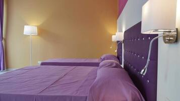 A hotel room with a bed, a nightstand, and a wall-mounted lamp.