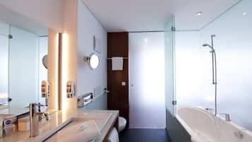 Un baño moderno con un espejo grande, dos lavamanos, una bañera y un box de ducha con paredes de cristal.