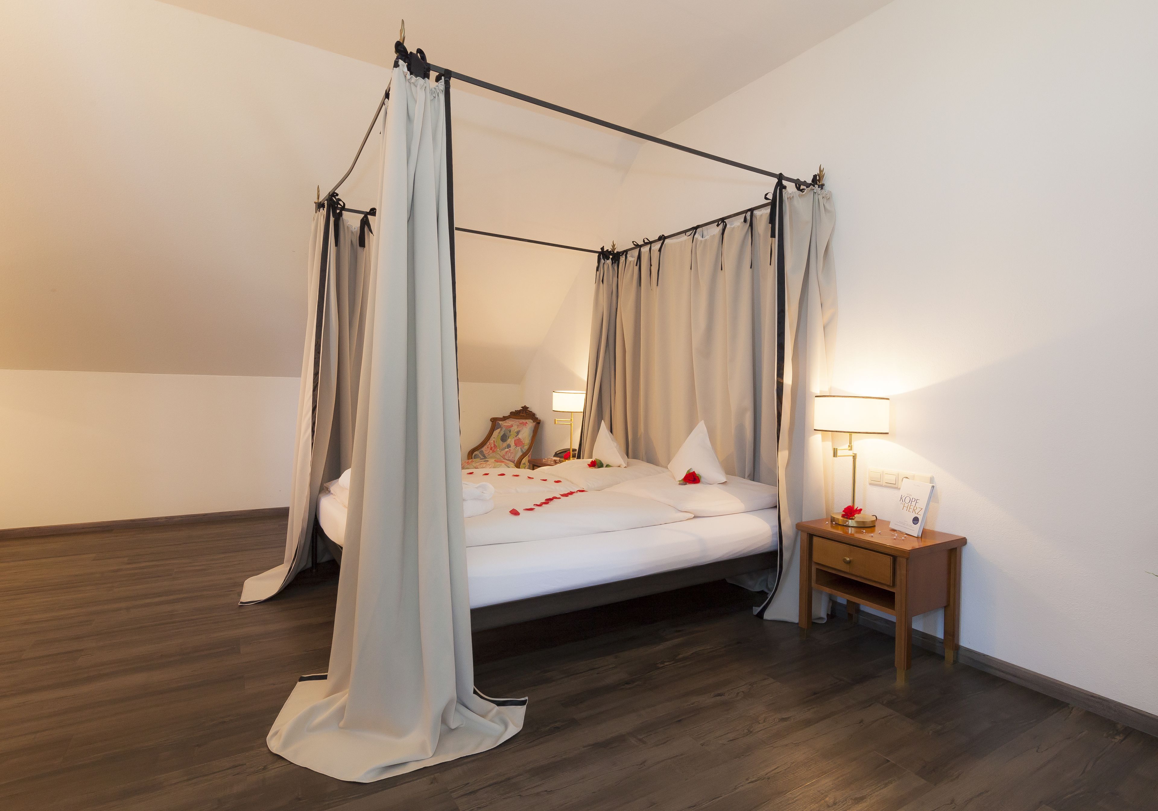 A four-poster canopy bed with a wooden nightstand beside it.