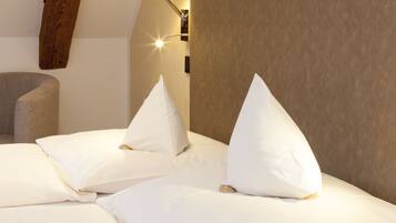 A neatly made bed with white pillows and a wooden headboard.