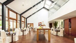 Ein geräumiges Zimmer mit Holzboden, großen Fenstern und einer hohen Decke mit Dachfenstern.