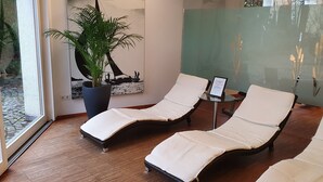 Ein Zimmer mit zwei Lounge-Sesseln, einer Topfpflanze und einem Gemälde.