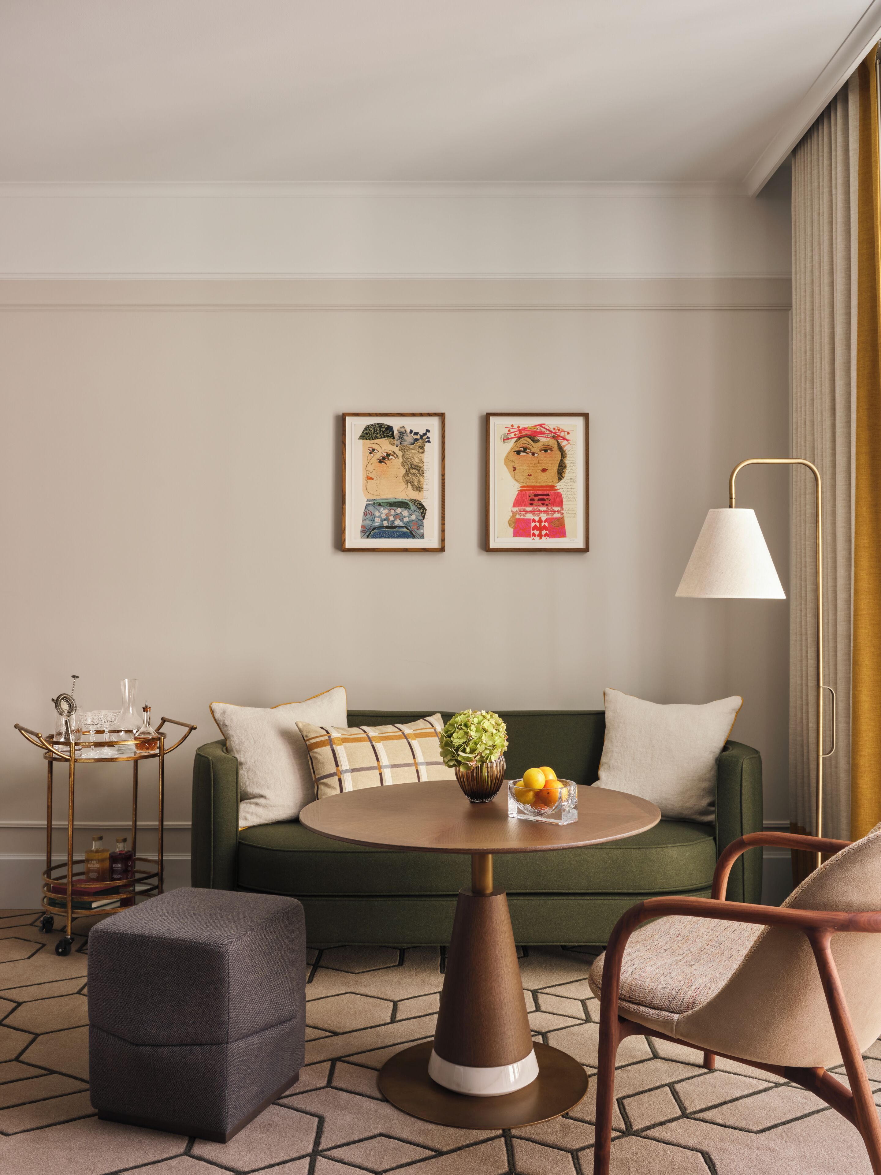 A room with a green sofa, a round coffee table, a side table with a lamp, and artwork on the wall.
