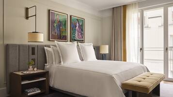 A hotel room with a large bed, bedside tables, a bench, and artwork on the wall.