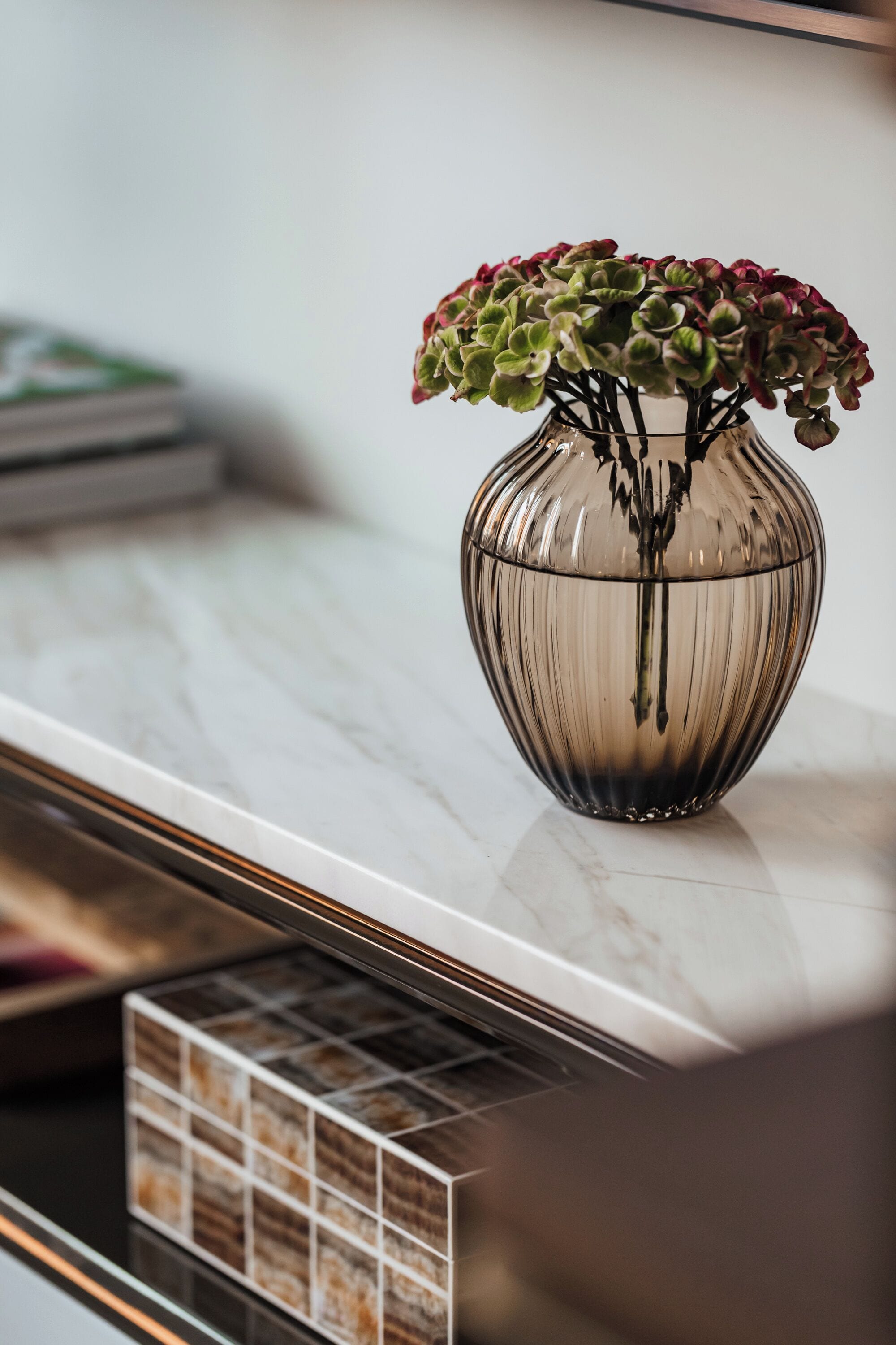 A clear glass vase with a plant on a marble countertop.