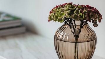 A clear glass vase with a plant on a marble countertop.