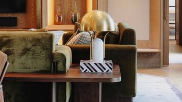 Una sala de estar moderna con una pared de acento de madera, un televisor de pantalla plana, un sofá verde, una mesa de centro y una lámpara.