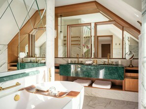 Une salle de bain moderne avec un grand miroir, des plans de travail en marbre et un meuble-lavabo en bois.