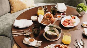 Una mesa redonda para comer con alimentos para el desayuno, incluyendo pan, salchicha y un tazón de sopa.