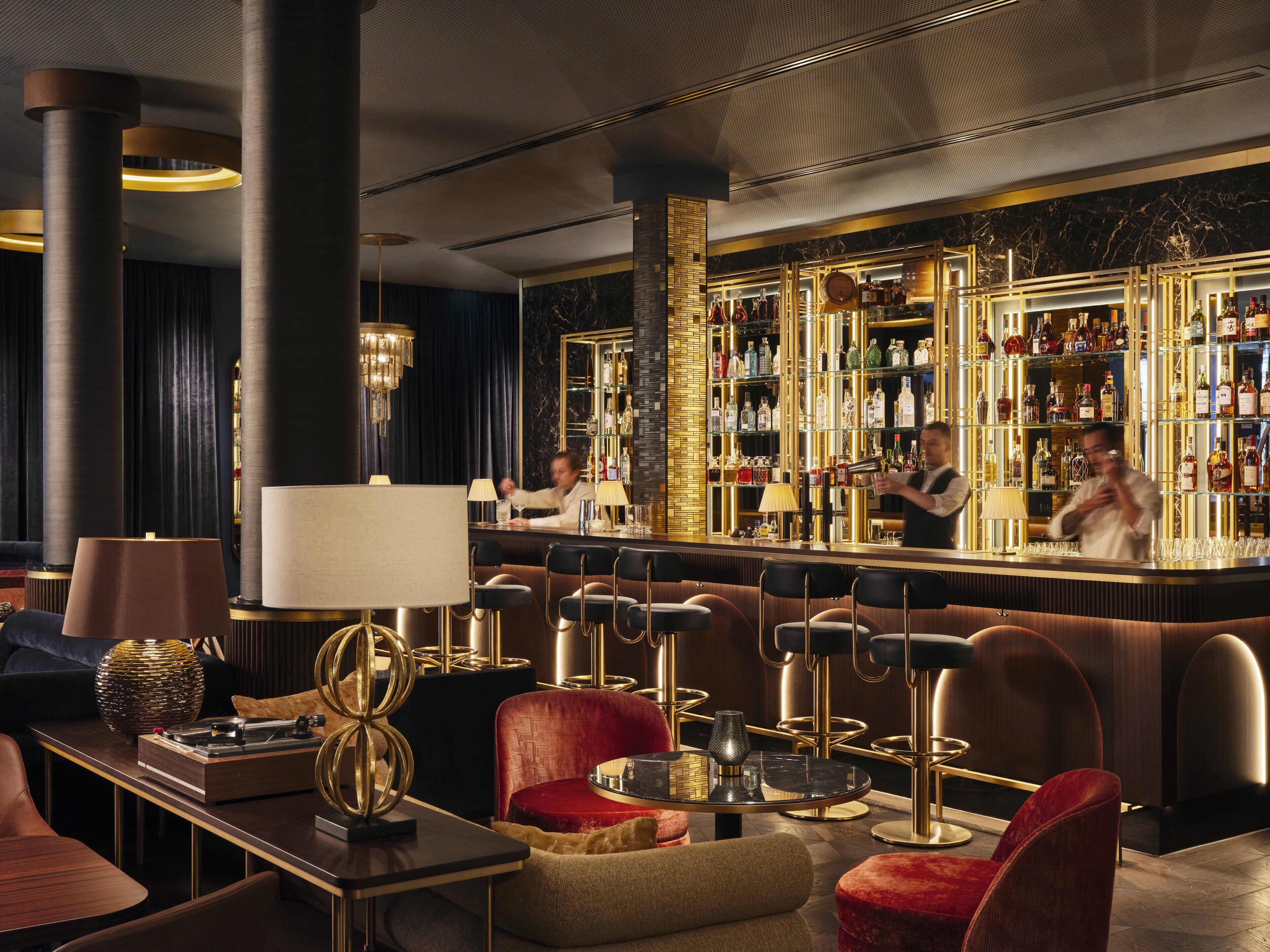 A bar area with a bartender, bar stools, and a well-stocked liquor shelf.