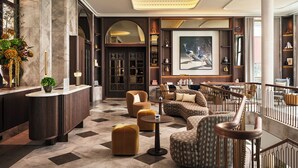 A lobby with a reception desk, seating areas, a large painting, and a staircase. - Rosewood Munich (Munich)