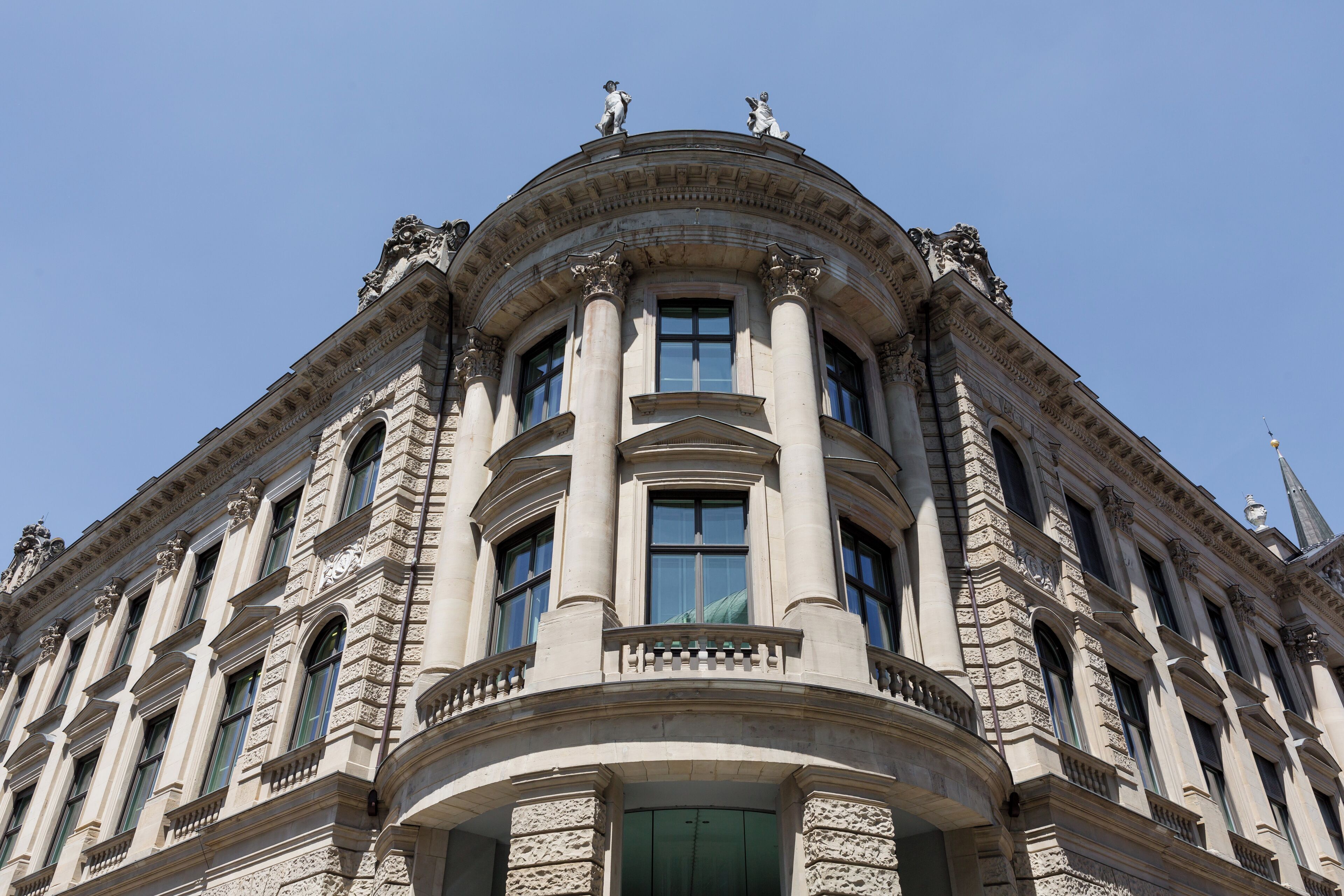 A corner of a historic building with classical architecture, featuring ornate columns and statues.
