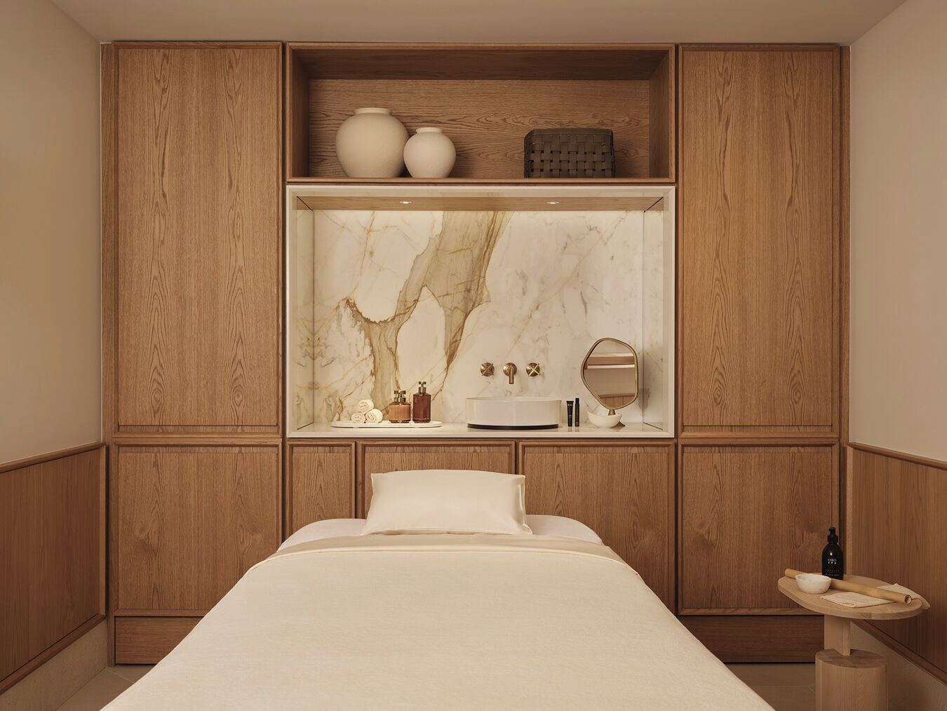 Une chambre à coucher avec un lit, une coiffeuse avec un miroir et une étagère ornée d’objets décoratifs.