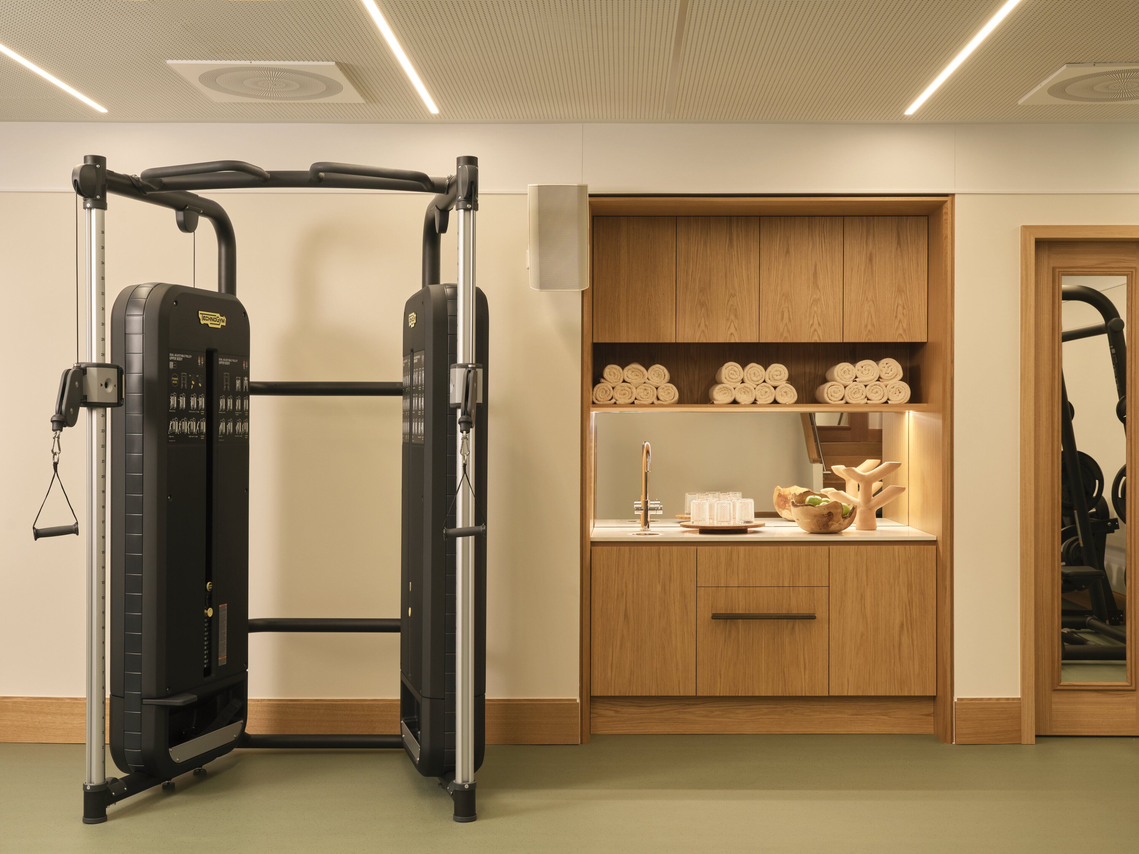 Ein Fitnessraum mit Kraftgerät, Holzausstattung und Spiegel.