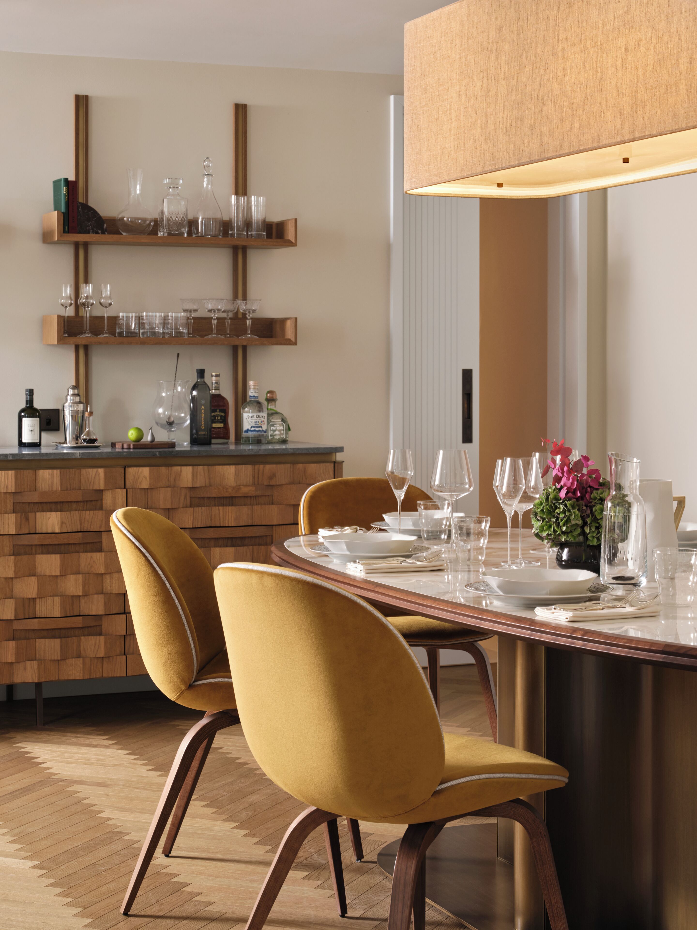 A dining area with a wooden table, two chairs, and a hanging light fixture.