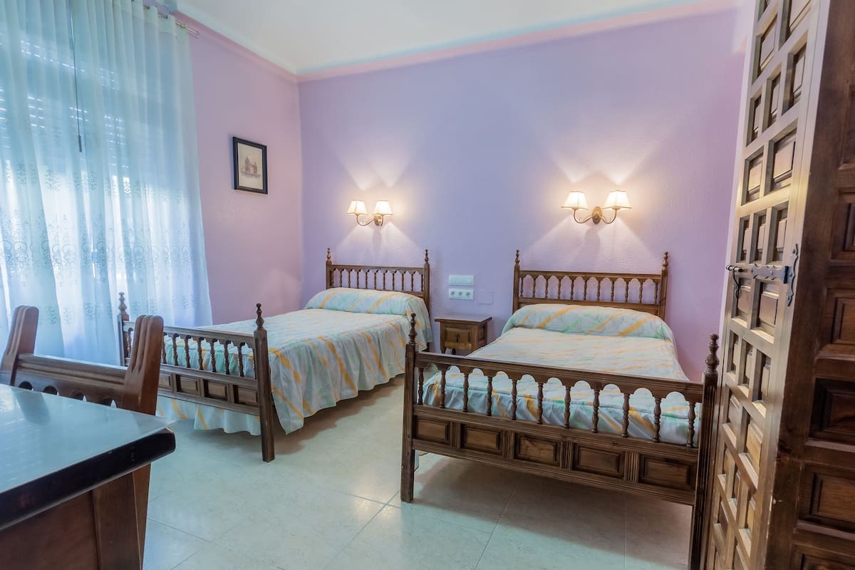 A room with two wooden beds, a desk, and a chair.