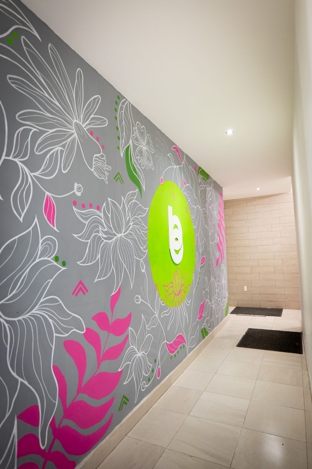 Ein Flur mit dekorativer Wand, verziert mit floralen Mustern und einem auffälligen, ovalen, grünen Bereich mit dem weißen Buchstaben 'b'.
