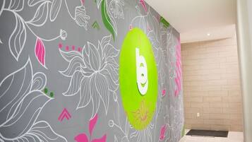 Ein Flur mit dekorativer Wand, verziert mit floralen Mustern und einem auffälligen, ovalen, grünen Bereich mit dem weißen Buchstaben 'b'.