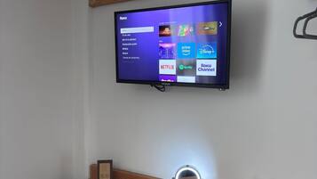 A room with a TV mounted on the wall displaying a streaming service interface.